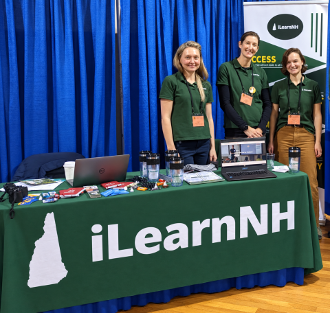 iLearnNH team stands around table at conference